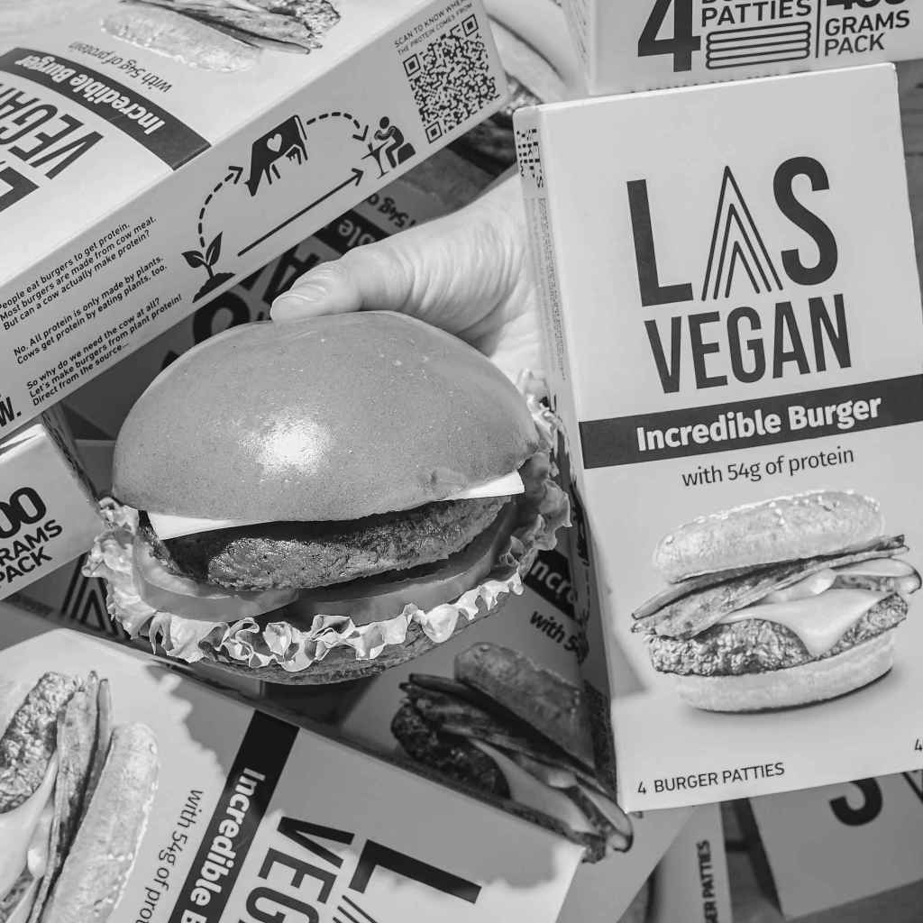 hand holding vegan burger surrounded by burger boxes